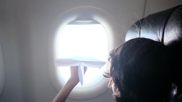 Back View Boys Plane Looks Dreamily Out Window Plays Paper — Stock Video