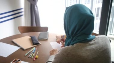 6 ve 8 yaşındaki çocuklarına evlerindeki okul görevlerinde rehberlik eden tesettürlü Müslüman bir anneye tanık olun.