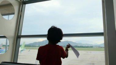 Çocuk havaalanında kağıt uçakla eğleniyor. 