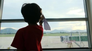 Çocuk havaalanında kağıt uçakla eğleniyor. 