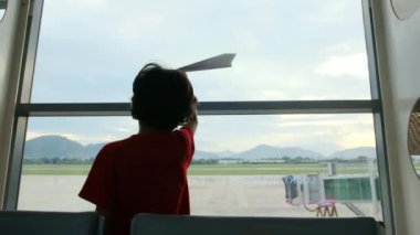 Çocuk havaalanında kağıt uçakla eğleniyor. 