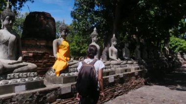 Sırt çantalı bir kadın Güneydoğu Asya tapınağında yürüyor.