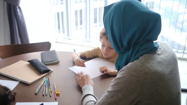 イスラム教徒の母親が 6歳と8歳の子供たちを自宅で学校の仕事を通して指導し 教育の家族を混同しているのを目の当たりにする — ストック動画