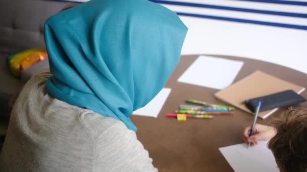 イスラム教徒の母親が 6歳と8歳の子供たちを自宅で学校の仕事を通して指導し 教育の家族を混同しているのを目の当たりにする — ストック動画