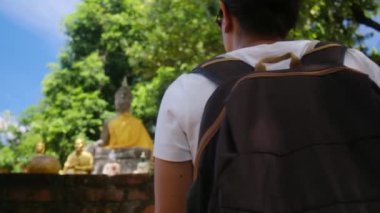 Sırt çantalı bir kadın Güneydoğu Asya tapınağında yürüyor.