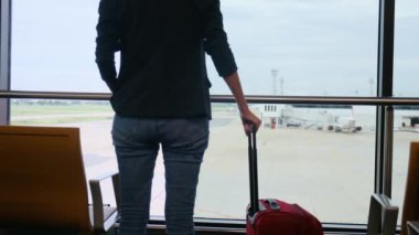 Solo gezgin havaalanı penceresinin yanında bavuluyla bekliyor, pistteki uçaklara bakıyor, macera beklentisini yakalıyor. Gezgin şehveti, havaalanı sahneleri, seyahat anları..