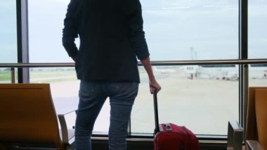 Solo gezgin havaalanı penceresinin yanında bavuluyla bekliyor, pistteki uçaklara bakıyor, macera beklentisini yakalıyor. Gezgin şehveti, havaalanı sahneleri, seyahat anları..