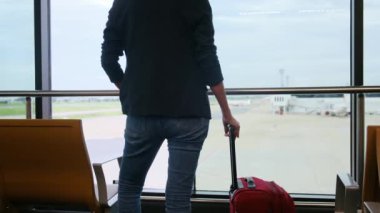 Solo gezgin havaalanı penceresinin yanında bavuluyla bekliyor, pistteki uçaklara bakıyor, macera beklentisini yakalıyor. Gezgin şehveti, havaalanı sahneleri, seyahat anları..