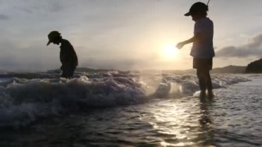 Sahilde oynayan çocuklar kumlu sahilde dalgalarla oynayan çocuklar mutlu bir aileyle denizde gezen çocuklar.