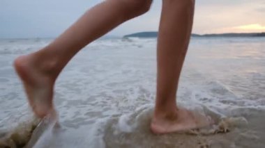 Yaz tatili ya da tatilde deniz ya da okyanus kıyısında kadın bacaklarıyla ayaklar, yürüme ve su. Sahilde, doğada ve özgürlükte bir kadın tek başına akıntıda, gelgitte ya da dalgalarda yürür.
