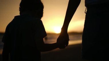Aile bağının iç açıcı özünü bir anne ve oğlunun silueti gibi huzur dolu bir sahilde büyüleyici bir günbatımının arka planında yaşayın.