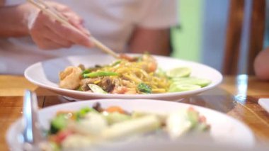 Gezgin Asyalı kadın geleneksel sokak yemekleri alışverişini ve yemeyi seviyor.. 