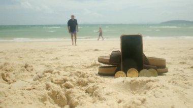 Teknoloji, tatil ve yaz tatili kavramı - kripto para birimi, akıllı telefon ve plaj kumlarında terlikler
