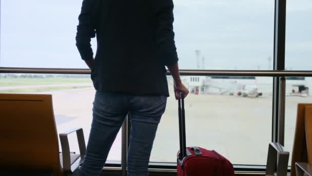 Egyéni Utazó Vár Bőröndjével Reptér Ablakánál Nézi Repülőket Kifutópályán Megragadja — Stock videók