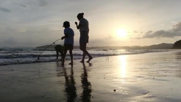 Glad Mor Går Langs Kystlinjen Med Sønnene Sine Ved Solnedgang – stockvideo