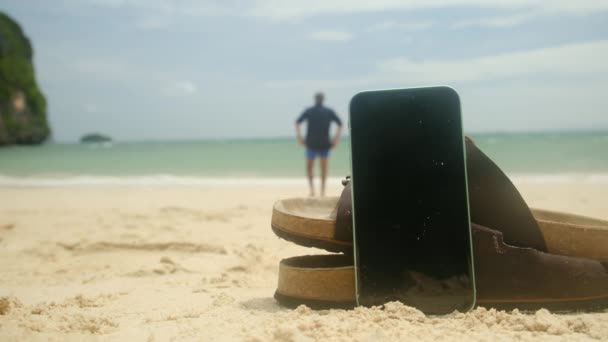 Σαγιονάρες Και Κινητό Τηλέφωνο Φόντο Αμμώδους Καλοκαιρινής Παραλίας Καλές Διακοπές — Αρχείο Βίντεο