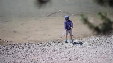 Ormanda nehre taş atan bir çocuk.