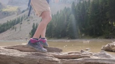 Düşen bir ağaç kütüğünde yürüyen çocuk ayakları.