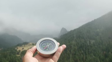 Doğal çam ormanı arka planında pusula elinde. Orman manzarasında el ele tutuşan pusula. Yaz dağlarında pusula arayan genç bir gezgin..