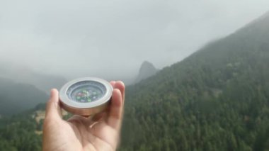 Doğal çam ormanı arka planında pusula elinde. Orman manzarasında el ele tutuşan pusula. Yaz dağlarında pusula arayan genç bir gezgin..