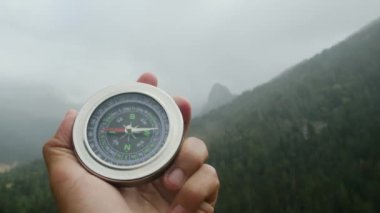 Doğal çam ormanı arka planında pusula elinde. Orman manzarasında el ele tutuşan pusula. Yaz dağlarında pusula arayan genç bir gezgin..