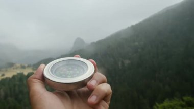 Doğal çam ormanı arka planında pusula elinde. Orman manzarasında el ele tutuşan pusula. Yaz dağlarında pusula arayan genç bir gezgin..