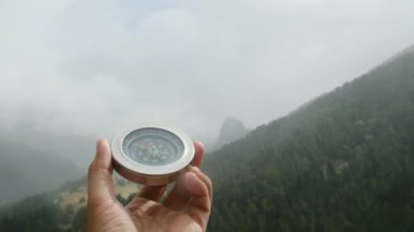 Doğal çam ormanı arka planında pusula elinde. Orman manzarasında el ele tutuşan pusula. Yaz dağlarında pusula arayan genç bir gezgin..