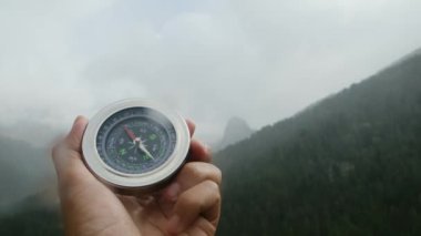 Doğal çam ormanı arka planında pusula elinde. Orman manzarasında el ele tutuşan pusula. Yaz dağlarında pusula arayan genç bir gezgin..