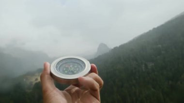 Doğal çam ormanı arka planında pusula elinde. Orman manzarasında el ele tutuşan pusula. Yaz dağlarında pusula arayan genç bir gezgin..
