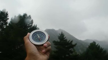 Doğal çam ormanı arka planında pusula elinde. Orman manzarasında el ele tutuşan pusula. Yaz dağlarında pusula arayan genç bir gezgin..