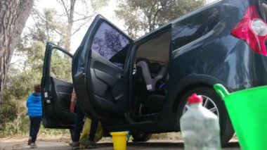 Çocuklar anneleriyle birlikte dikkatli bir şekilde araba temizliyorlar.