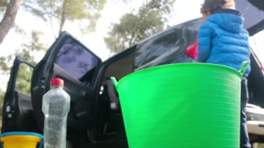 Çocuklar anneleriyle birlikte dikkatli bir şekilde araba temizliyorlar.