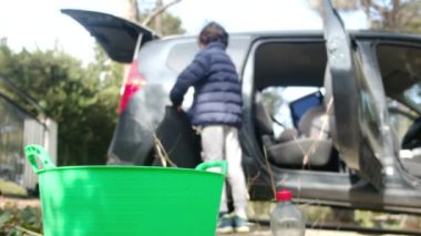 Çocuklar anneleriyle birlikte dikkatli bir şekilde araba temizliyorlar.