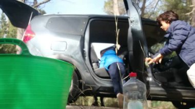 Çocuklar anneleriyle birlikte dikkatli bir şekilde araba temizliyorlar.