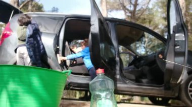 Çocuklar anneleriyle birlikte dikkatli bir şekilde araba temizliyorlar.