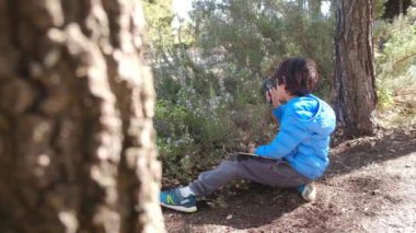Genç doğa bilimci çocuk büyüteçle ormanın doğasını inceliyor. seyahat macera konsepti.