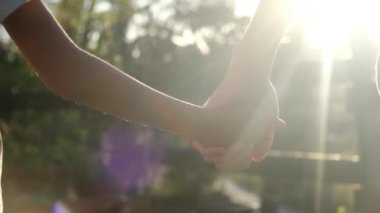 Anne ve çocuk gün batımında el ele tutuşuyorlar. Oğul ya da kız olarak siluet anne elini tutuyor. Güneş patlamaları. Aile, güven, aşk ve mutluluk kavramı