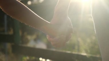 Anne ve çocuk gün batımında el ele tutuşuyorlar. Oğul ya da kız olarak siluet anne elini tutuyor. Güneş patlamaları. Aile, güven, aşk ve mutluluk kavramı
