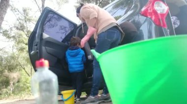 Çocuklar anneleriyle birlikte dikkatli bir şekilde araba temizliyorlar.