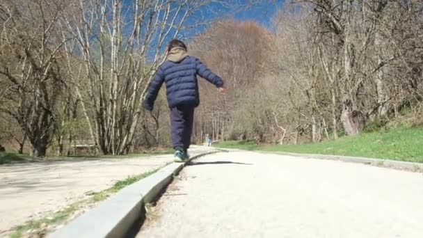 Fiú Végigsétál Járdán Megtartja Egyensúlyát — Stock videók
