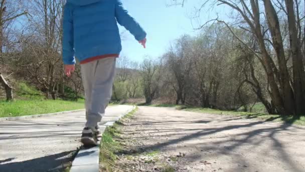Jongen Loopt Langs Stoeprand Houdt Zijn Evenwicht — Stockvideo