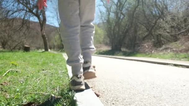 Αγόρι Περπατάει Στο Πεζοδρόμιο Και Κρατάει Την Ισορροπία Του — Αρχείο Βίντεο