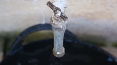 Lavabonun musluğundan bir damla su yavaş çekimde, musluğun yakınına düşer. Su yok, iklim değişikliği yok..