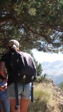Genç yürüyüş meraklılarıyla güneşli mevsimlerin tadını çıkarın. Oğullarıyla dağlarda yürüyüş yapan bir kadın. 