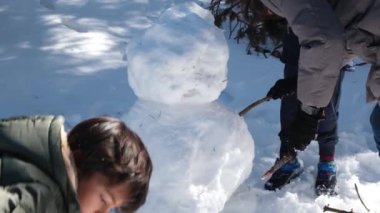 Karda oynayıp kardan adam yapan mutlu çocuklar.