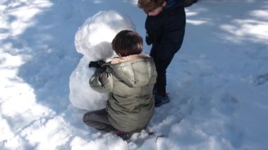 Karda oynayıp kardan adam yapan mutlu çocuklar.