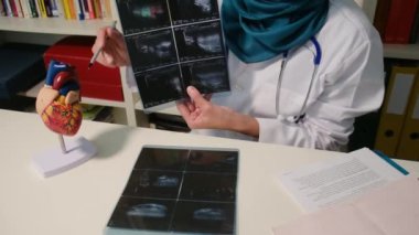 Hastanedeki masada oturan Müslüman kardiyoloji uzmanının röntgenlerini yakın plan çekin.
