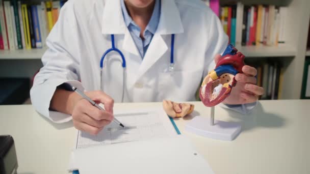 テーブルに座って 病院で病気を説明する心臓科医の近くのビュー — ストック動画