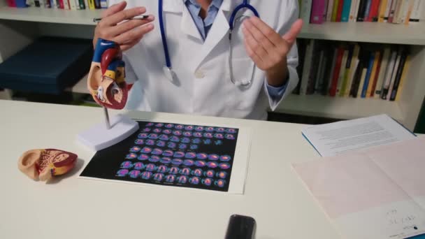 テーブルに座って 病院で病気を説明する心臓科医の近くのビュー — ストック動画