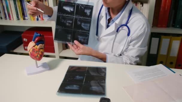 Крупный План Кардиолога Показывающего Рентген Сидящего Столом Больнице — стоковое видео